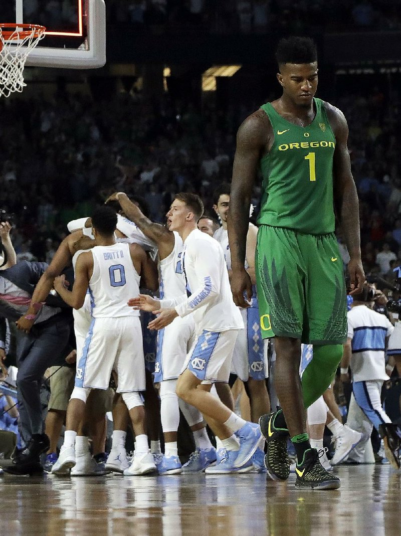 Oregon’s Jordan Bell walks off the court as North Carolina players celebrate after the Tar Heels’ 77-76 victory over the Ducks on Saturday at the Final Four in Glendale, Ariz.