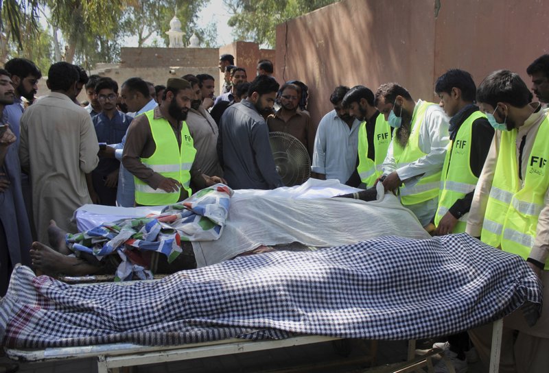 Pakistani volunteers and local residents gather around the bodies of people who were killed in a local shrine, outside the morgue of a hospital in Sarghodha, Pakistan, Sunday, April 2, 2017. Pakistani police say the custodian of the shrine and his accomplices have murdered 20 devotees in eastern Punjab province as part of a group cult ritual.