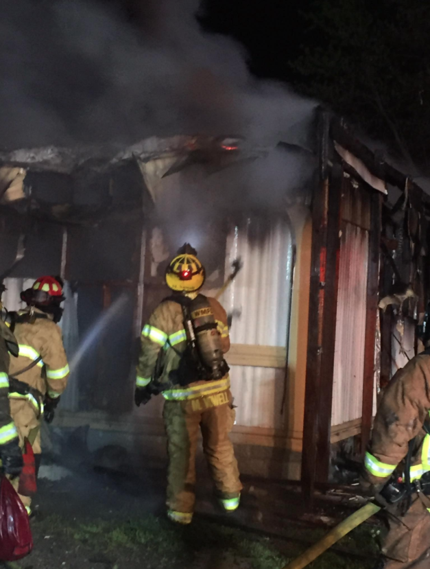 A firefighter works to extinguish a blaze at a mobile home Sunday.