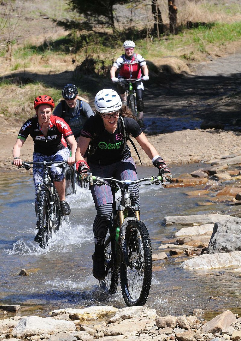 Tandie Bailey of Bentonville leads riders across Lee Creek during a group ride at the 28th annual Ozark Mountain Bike Festival in April 2016 at Devil’s Den State Park.
