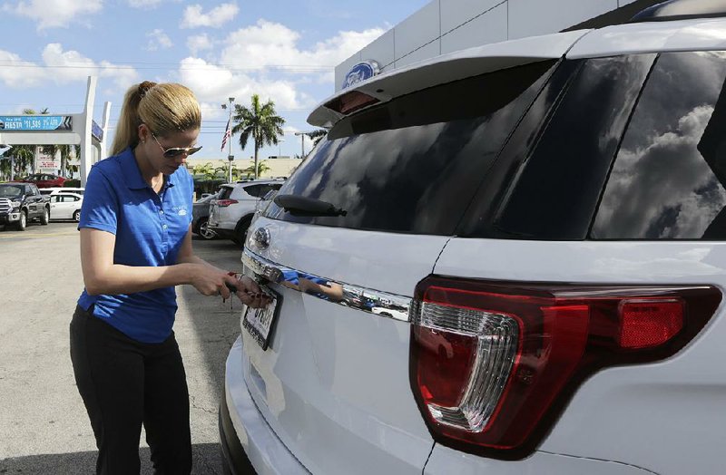 A salesman at a Ford dealership in Hialeah, Fla., removes the dealer tag from a 2017 Ford Explorer in this file photo. Ford was among several automakers to report falling sales in March.