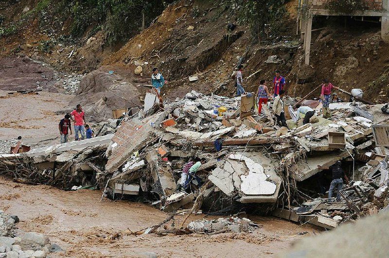 People walk over the debris of a collapsed building Sunday in Mocoa, Colombia.