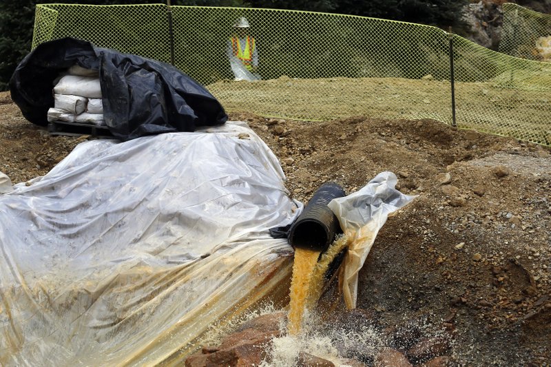 In this Aug. 12, 2015 photo, an Environmental Protection Agency contractor works on the cleanup in the aftermath of the blowout at the Gold King Mine, overseeing water flowing from the mine into a series of sediment retention ponds, mitigating damage from the spill of toxic wastewater, outside Silverton, Colo. 