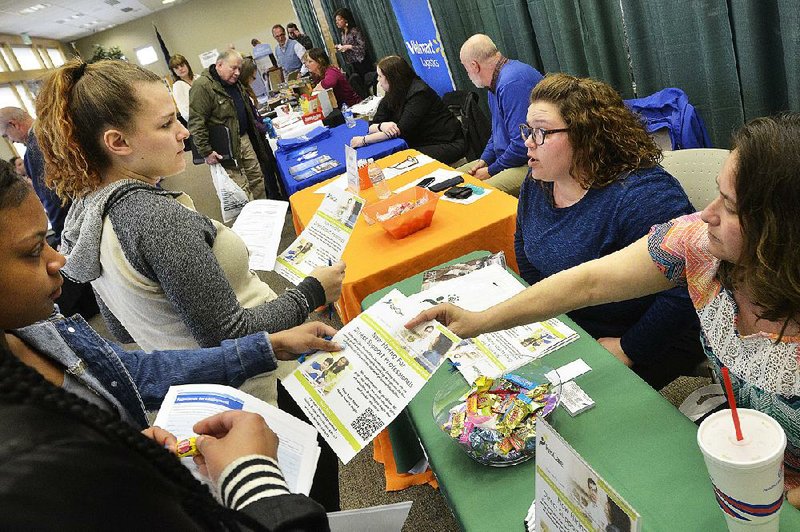 A supervisor and a staff worker of a residential services company (both seated) talk to job seekers Tuesday at a job fair in Marion, Ind.