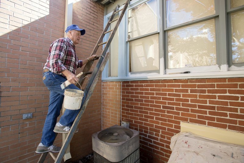 Bob Rich of Rogers paints the window frames at the Hawkins House on Thursday in Rogers. The Rogers Historical Museum Commission met Thursday to discuss the museum’s annex repair, the expansion and maintenance being done to the Hawkins House.