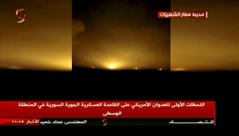 This frame grab from video provided by Ikhbaria TV, a Syrian pro-government TV channel that is consistent with independent AP reporting, shows flames rising from U.S. Tomahawk missiles which hit the Shayrat air base, southeast of Homs, Syria, early Friday April, 7, 2017. The Arabic on the screen reads: "Around the Shayrat airport, top right, the first moments of the American aggression on the air base in the central region, center bottom." (Ikhbaria TV, via AP)
