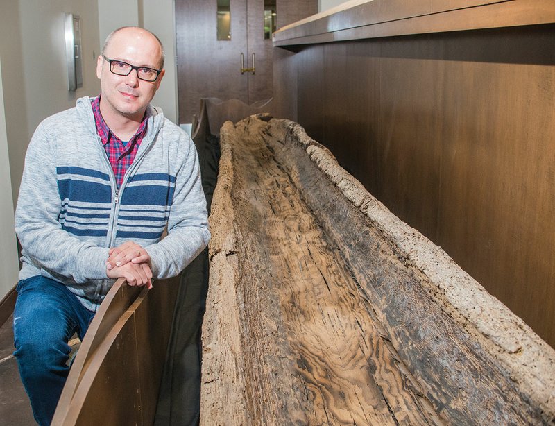 Brad Jordan, economic development director for the city of Benton, sits next to the Peeler Bend Canoe. The canoe, which was found in 1999 by Charles Greene, is believed to be more than 900 years old and is now on display at the new River Center at Riverside Park in Benton.