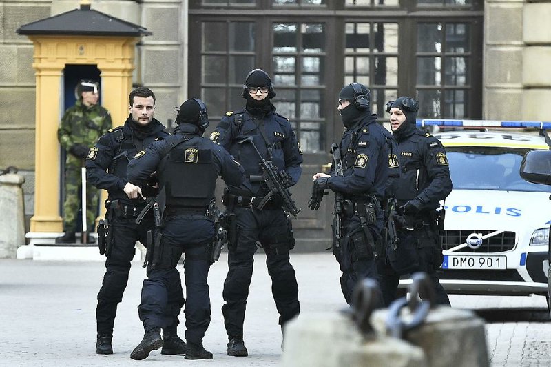 Armed police stand guard Friday outside Stockholm Castle after a hijacked beer-delivery truck crashed into pedestrians outside a department store in Stockholm.