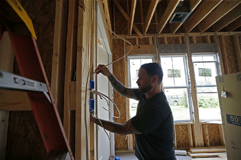 Quinn Lovetro, an electrician with Tasch Electric, works on a home being built by Zach Tyson of Tyson Construction in Destrehan, La., last month.