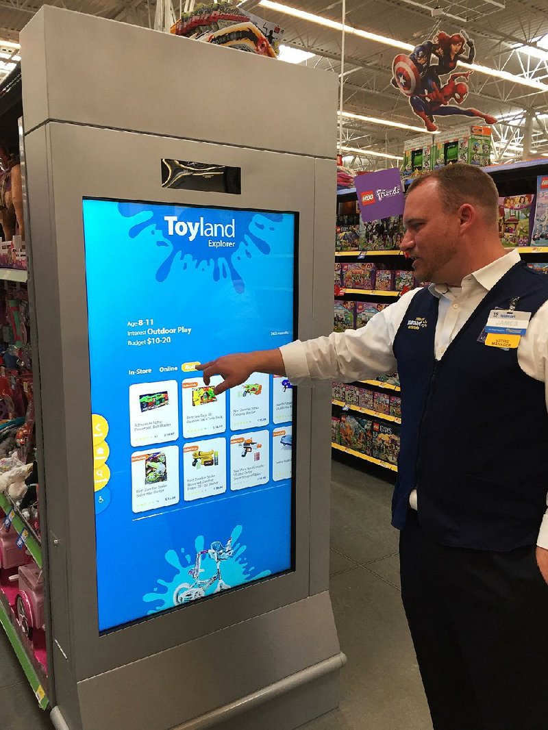 Store manager James Schroder demonstrates a large touch screen in the toy department at a Wal-Mart supercenter in Orlando, Fla. The touch screen gives customers a chance to sift through the retailer’s in-store and online catalog.