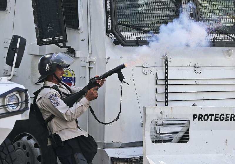 A Venezuelan police officer fires tear gas toward demonstrators Saturday during a protest in Caracas. 