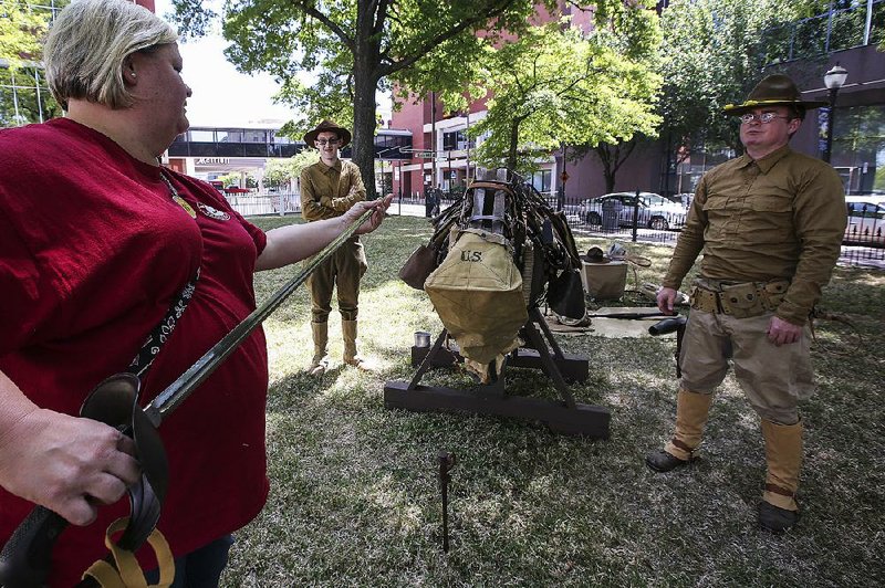 Amber Bingham of Clinton, Ala., (from left) checks out a saber as re-enactors Blake Phillips of Donaldson and Randall Watts of Black Rock take part in an event Saturday at the Old State House Museum in Little Rock to commemorate the 100th anniversary of the U.S.’ entry into World War I. 