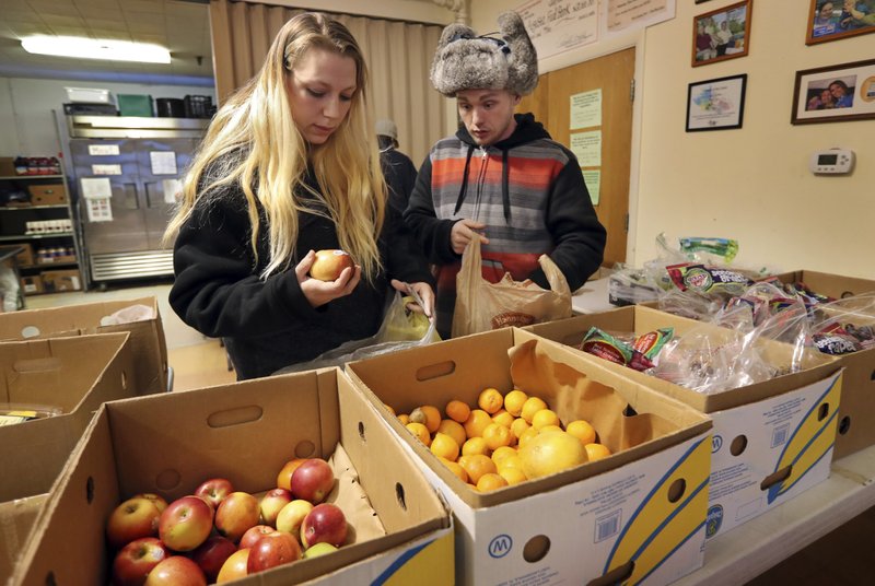 Sunny Larson (left) and Zak McCutcheon pick produce March 27 while gathering provisions to take home at the Augusta Food Bank in Augusta, Maine.