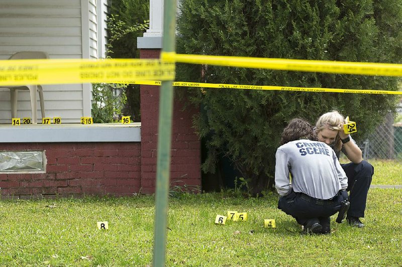 Little Rock crime scene investigators search for bullet casings on the porch and yard of a home at West 27th and Washington streets, where two 16-year-olds were shot Sunday.