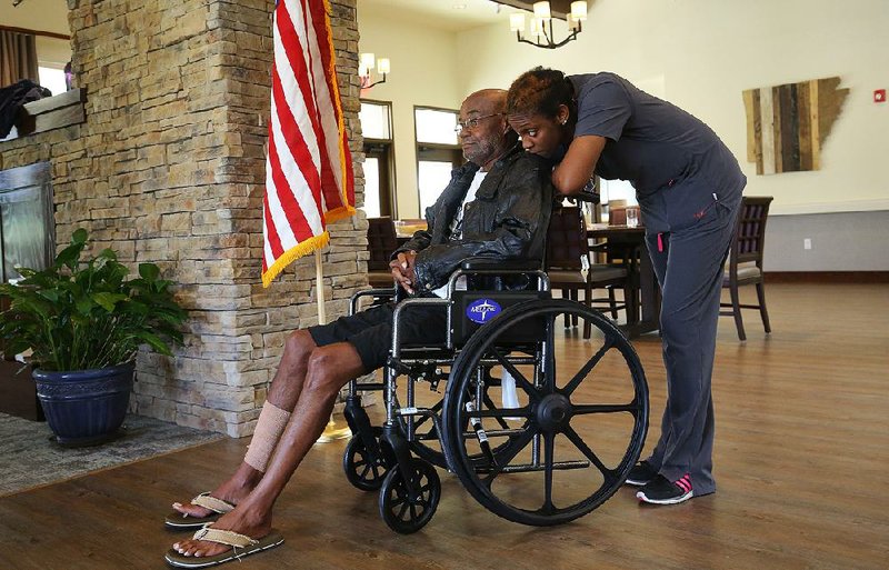 Nursing assistant Katrina Allison rests her head on the shoulder of resident Sammy Johnson as they wait to get his blood pressure checked before dinner in a cottage at the new Arkansas State Veterans Home in North Little Rock on Wednesday.