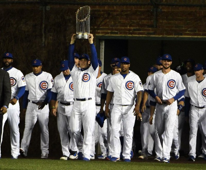 Chicago Cubs first baseman Anthony Rizzo (center) is joined by his teammates as he carries the 2016 World Series trophy before the team’s home opener against the Los Angeles Dodgers on Monday night at Wrigley Field. 