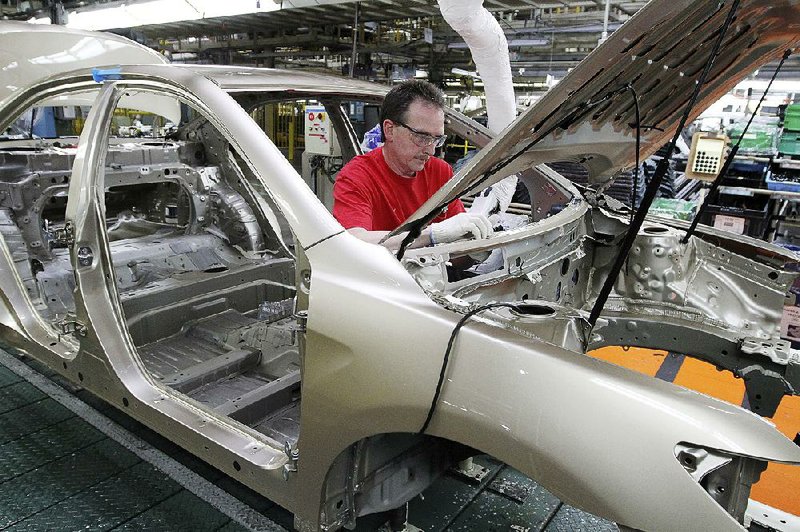 A worker installs a dashboard part in a Toyota Camry at the automaker’s manufacturing plant in Georgetown, Ky., in this file photo. The company plans to update equipment and build a new paint shop as part of a $1.33 billion investment in the factory.