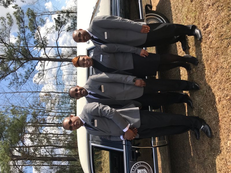 A legacy: From left to right, the Rev. Felton Burgies, chaplain, owner and managing director Robert Henderson, co-owner and apprentice funeral director Natashia Henderson and the Rev. Barry Dodson pose for a faculty picture with the Sim’s Mortuary hearse.