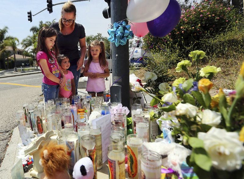 Lena Hammerling, her daughters Melissa (left) and Maci (right), and another child look Tuesday at a sidewalk memorial dedicated to the teacher and student who were fatally shot Monday at North Park Elementary School in San Bernardino, Calif.