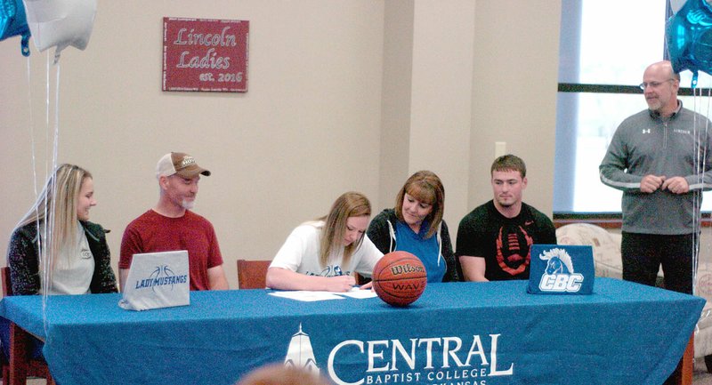 MARK HUMPHREY/ENTERPRISE-LEADER/Lincoln senior Kendra Cummings (center) signs a national letter of intent to play women&#8217;s college basketball for Central Baptist College, of Conway, on Thursday. She was accompanied by her family and friends from left: teammate Darrian McConnell, her father Darrien Cummings, her mother Tennille Cummings, and brother Tyler Cummings while Lincoln athletic director Deon Birkes looks on.