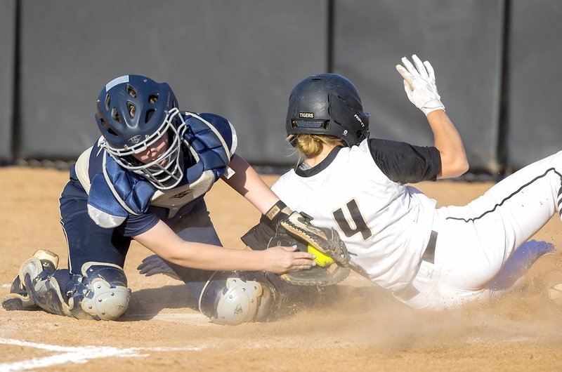 Bentonville High’s Payton Wildeman (right) slides safely into home Tuesday ahead of the tag from Bentonville West catcher Sydney Sneed in Bentonville.