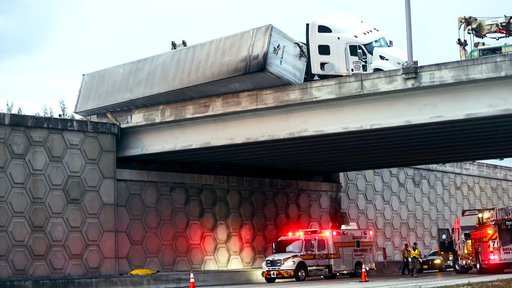 A tractor-trailer dangles off the Congress Avenue overpass over I-95 early Wednesday, April 12, 2017, in West Palm Beach, Fla. 