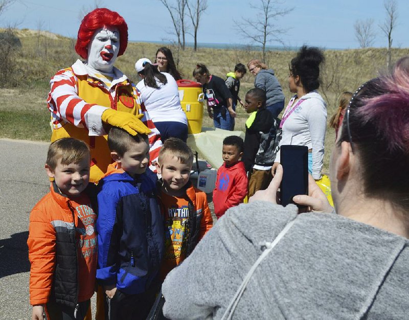 Ronald McDonald poses with children Saturday at an Easter egg hunt in Michigan City, Ind. Mc-Donald’s plans to introduce a mobile ordering system that will collect data to help the burger chain customize the way it interacts with customers. 