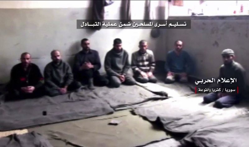 Syrian rebels wait to be released in this video frame grab from the Syrian military. The Arabic words on the screen read: “Handing over the fighter prisoners as part of the exchange deal.”