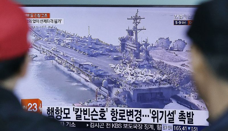 Commuters at a railway station Wednesday in Seoul, South Korea, watch a program showing an image of the aircraft carrier USS Carl Vinson, which is leading a battle group to waters off the Korean Peninsula in a show of force against North Korea and its nuclear program.