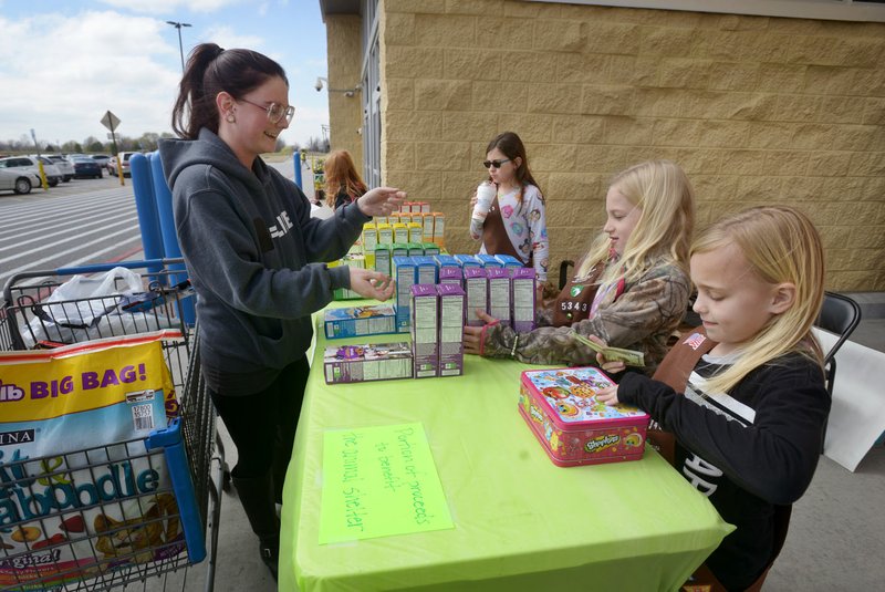 Janell Taylor (from left) of Elm Springs buys Girl Scout Cookies from Emma Griggs, Caroline Barnett and Olivia Tingley last month when Brownie Troop 5343 held a sale outside the Wal-Mart Supercenter on Elm Springs Road in Springdale. The troop plans to donate $200 from the sale to the Springdale Animal Shelter and also was accepting donations to give cookies to the Springdale Police Department.