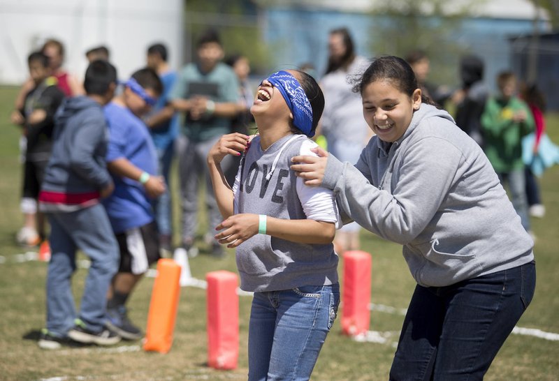 Karrelys Cardona (right), Decatur sixth-grader, helps guide Daisy Alonso, fifth-grader, through a blindfolded maze Wednesday on the Decatur football field. A group of eighth-graders organized the event, “Revolution 2021,” for Decatur Middle School students.