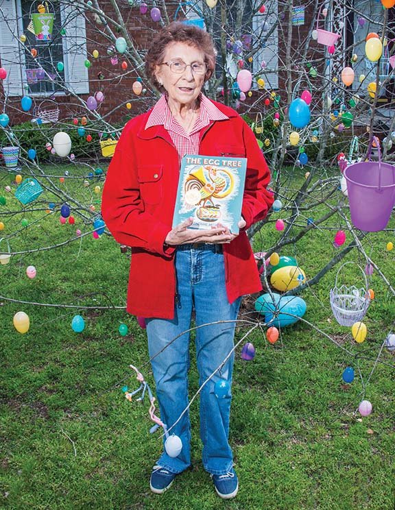Mary Ella Campbell of Dover holds The Egg Tree, the book that she read to her first-graders in the 1970s and that inspired the tradition of decorating a tree in her yard for Easter every year after she retired in 1985.