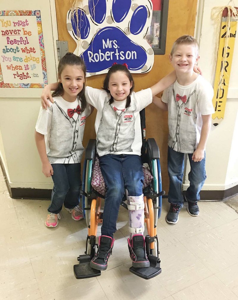 Second-grader Colleen Herron is surrounded by her best friends, Deandra Shehane and Spencer Seel. The students, along with others at Central Primary School and in the Arkadelphia community, are rallying together to support Colleen on her cancer journey and raise funds for the upcoming Relay for Life on Friday.