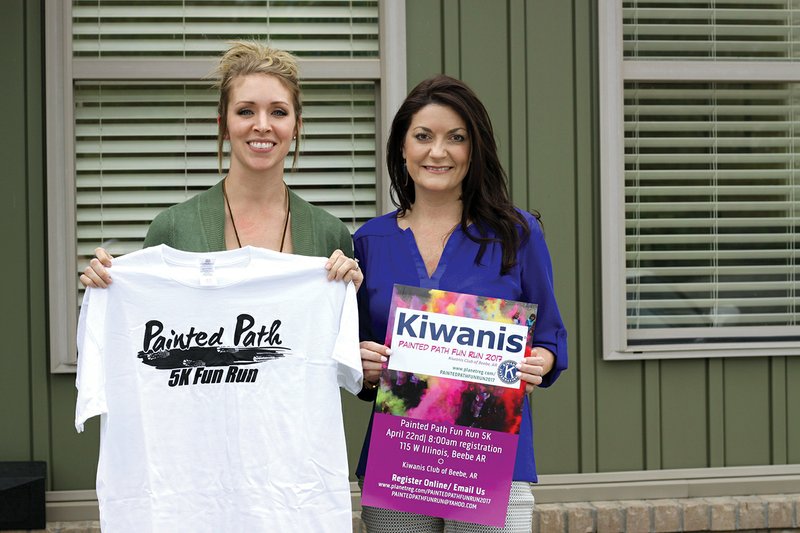 Lauren Shoot, president of the Kiwanis Club of Beebe, left, holds up the T-shirt for the Painted Path Fun Run 5K while Leslie Richardson displays the promotional sign for the race. All proceeds from the run will benefit the Kiwanis of Beebe Scholarship Fund.