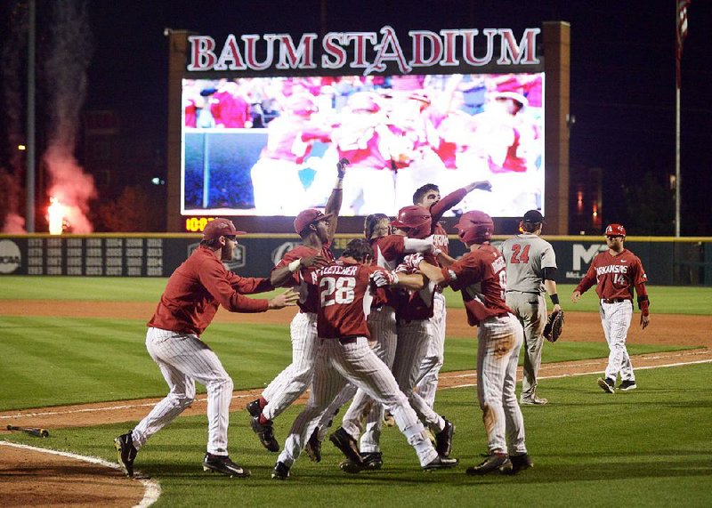 Arkansas players mob Evan Lee after he scored the winning run in the bottom of the 10th inning in the Razorbacks’ 5-4 victory over Georgia on Friday night at Baum Stadium in Fayetteville.