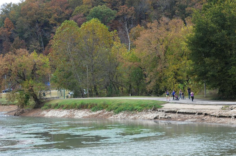 Pedestrians stroll across the Lake Bella Vista dam.