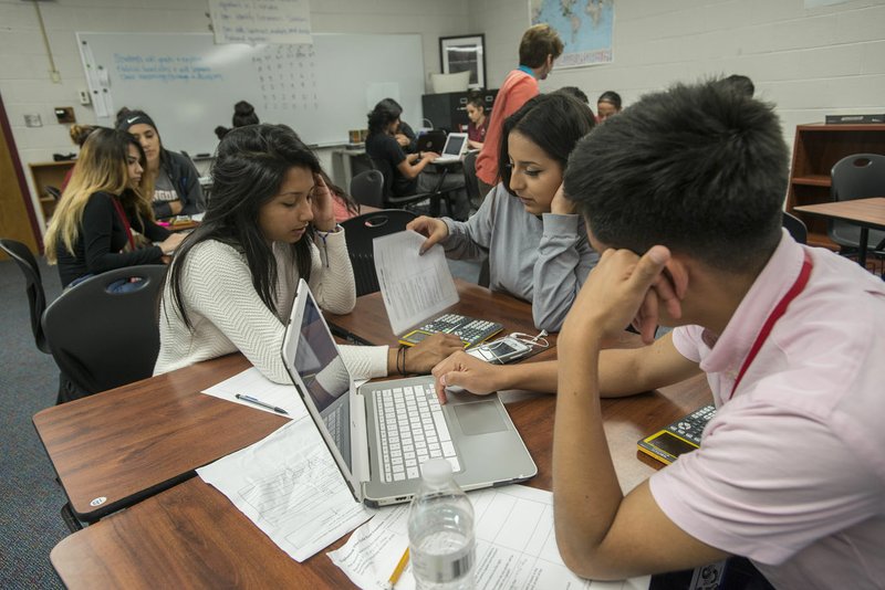 Jackie Escobar (from left), Amy Chacon and Michael Martinez work on a math problem Thursday in their Algebra II class at Springdale High School. The class uses more group-based learning to understand the material.