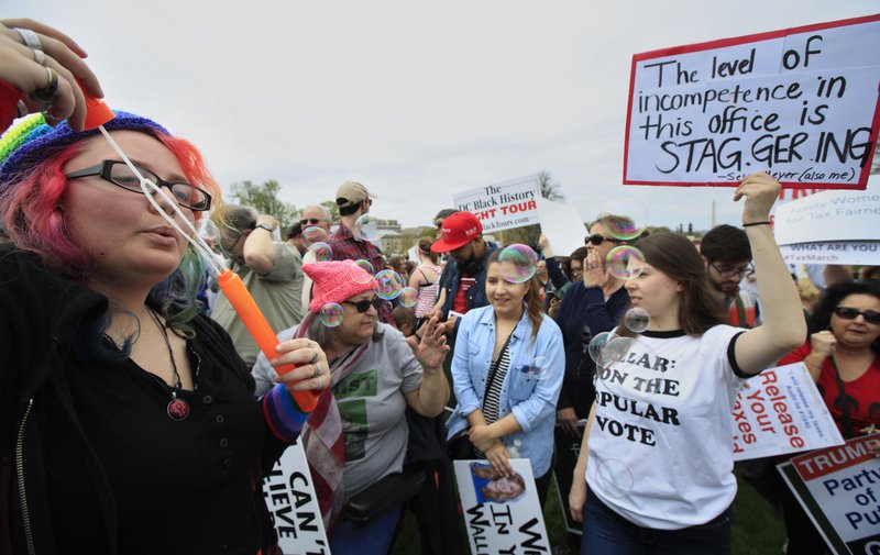 Sarah Holliger from Findley, Ohio, blows bubbles during a Tax Day demonstration on Capitol Hill in Washington, Saturday, April 15, 2017, calling on President Donald Trump to release his tax returns.