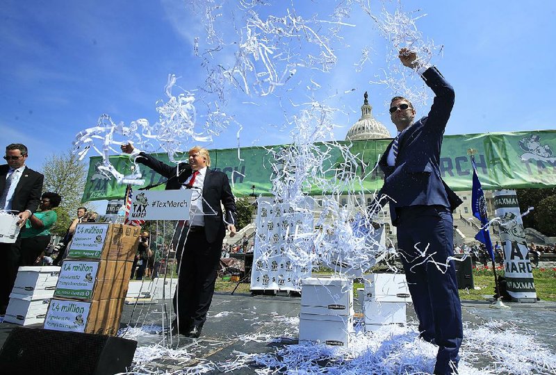 Paper is thrown to symbolize shredded tax returns as Anthony Atamanuik of Comedy Central, impersonating President Donald Trump, speaks Saturday during a demonstration in Washington.