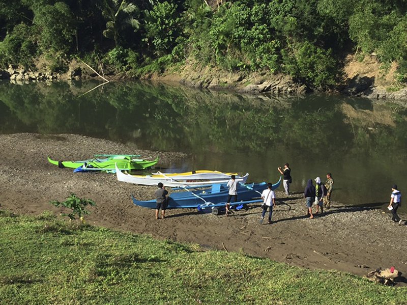 This undated photo provided by the Armed Forces of the Philippines on April 12, 2017, shows people stand by boats which the military said were used by Abu Sayyaf militants to enter the Ibananga River in Bohol province, central Philippines, as government troopers continue clearing operations. 