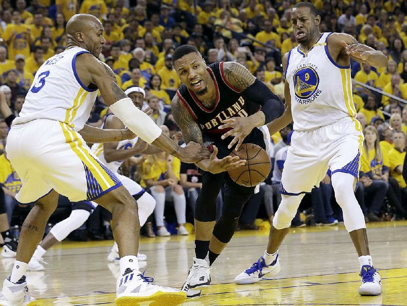 Portland guard Damian Lillard (center) loses the ball between Golden State forwards David West (3) and Andre Iguodala (9) in the second half of their NBA Western Conference playoff Sunday in Oakland. The Warriors, behind Kevin Durant’s 32 points, won the game 121-109.