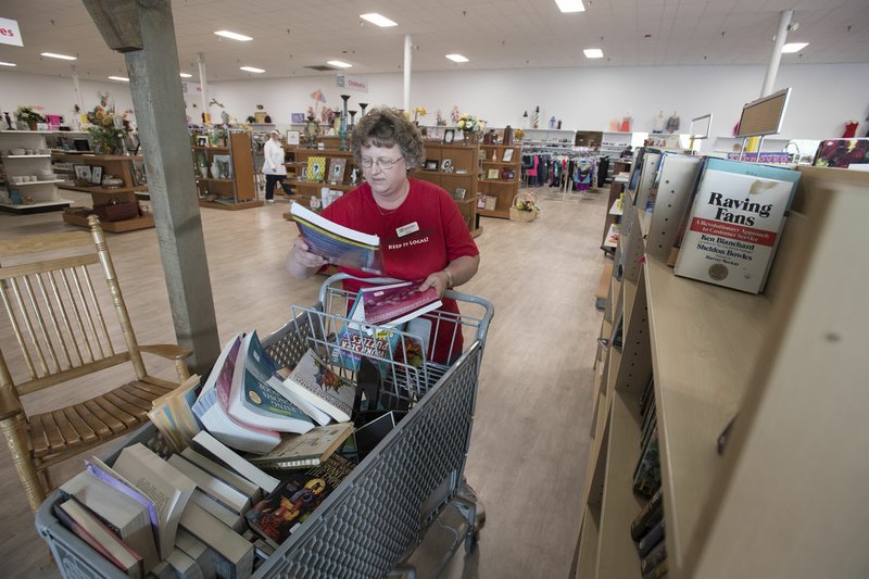 Alicia Barrett of Rogers sorts books Thursday at Rogers Samaritan Shop’s new location at the old Rogers Outdoor Sports location in the former Kmart building, 2115 W. Walnut in Rogers. The store has had record sales days since opening last Saturday.