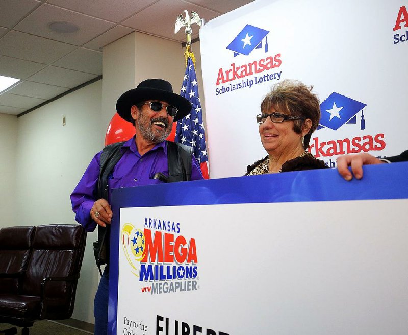 Eliberto Cantu and his wife, Anita, smile Monday while holding up their check from the Arkansas Scholarship Lottery for winning the Mega Millions jackpot.