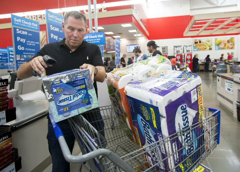 Scott Leach of Rogers scans items at a self-checkout station Tuesday at Sam’s Club in Bentonville. The company is working to build customer loyalty through private-label products.