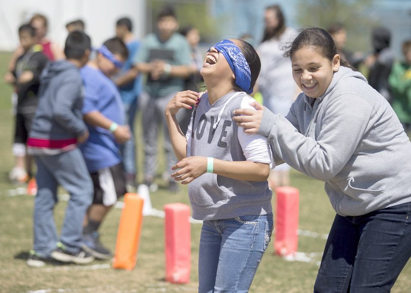 Photo by Jason Ivester Karrelys Cardona (right), Decatur sixth-grader, helps guide Daisy Alonso, fifth-grader, through a blindfolded maze Wednesday, April 12, 2017, on the Decatur football field. A group of Decatur eighth-graders organized the event, Revolution 2021, for Decatur Middle School students.