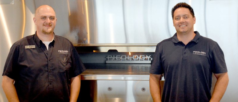 Michael Burchfiel/Herald-Leader Matt Bookout and Kyle Cook, both members of Pieology&#8217;s management in Siloam Springs, stand in front of their new pizza oven. Pieology&#8217;s soft opening on Saturday will benefit local charity Dustin&#8217;s Dream.