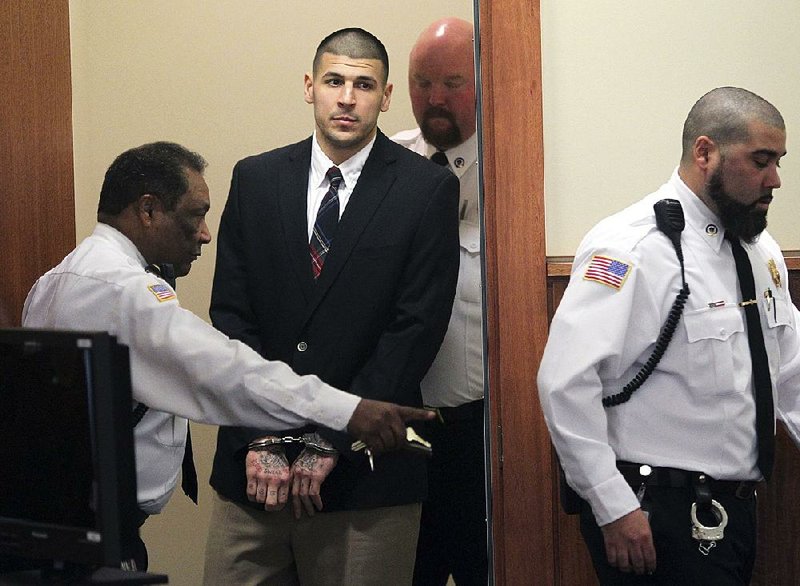 In this Monday, Dec. 23, 2013, file photo, former New England Patriots NFL football player Aaron Hernandez is led into his court appearance at the Fall River Superior Court in Fall River, Mass.