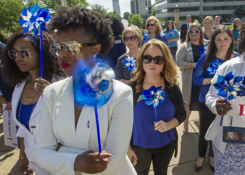 Donita Ross (from left), Marquisha Applewhite and other Children and Family Services Division workers from around the state participate in a rally at the Capitol on Wednesday in observance of National Child Abuse Prevention Month. The blue pinwheels symbolize child-abuse prevention.