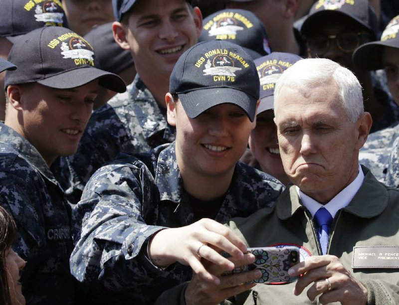 Vice President Mike Pence poses for a selfie with a U.S. serviceman aboard the USS Ronald Reagan during a visit to the nuclear-powered aircraft carrier docked at the Navy’s base in Yokosuka, Japan.