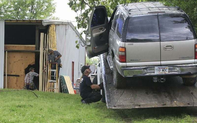 A tow truck operator loads a vehicle Wednesday afternoon as workers repair damage to a church building at the corner of Springer Boulevard and East Roosevelt Road in Little Rock after the vehicle, which had been pursued by police, struck the building.